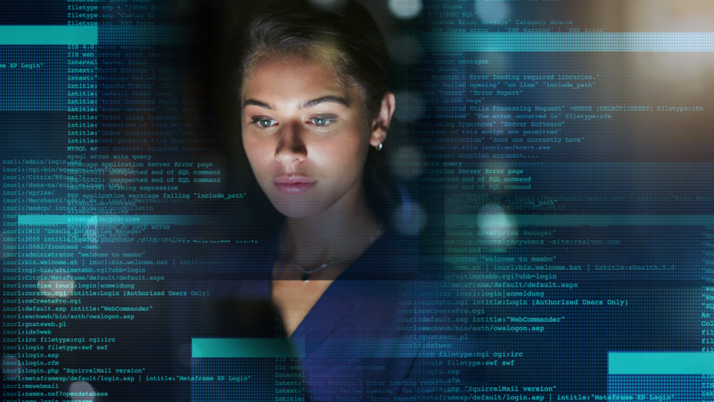 A woman focused on a computer screen, coding. The screen displays lines of code and technical information.